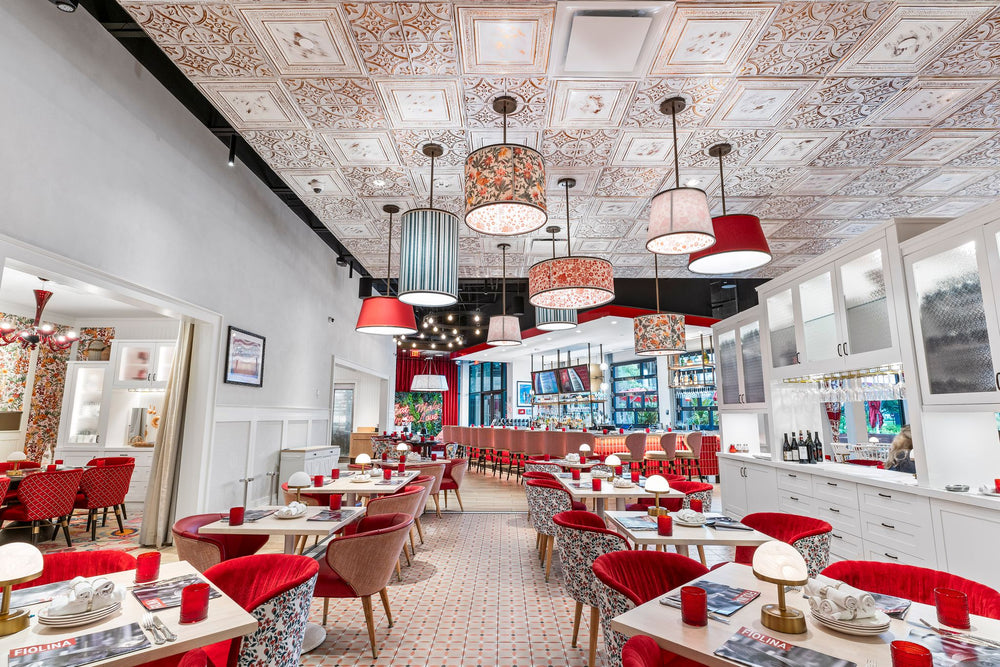 Bright restaurant interior with ornate white and copper tin ceiling tiles from American Tin Ceiling, mixed pendant lights, and red upholstered seating.